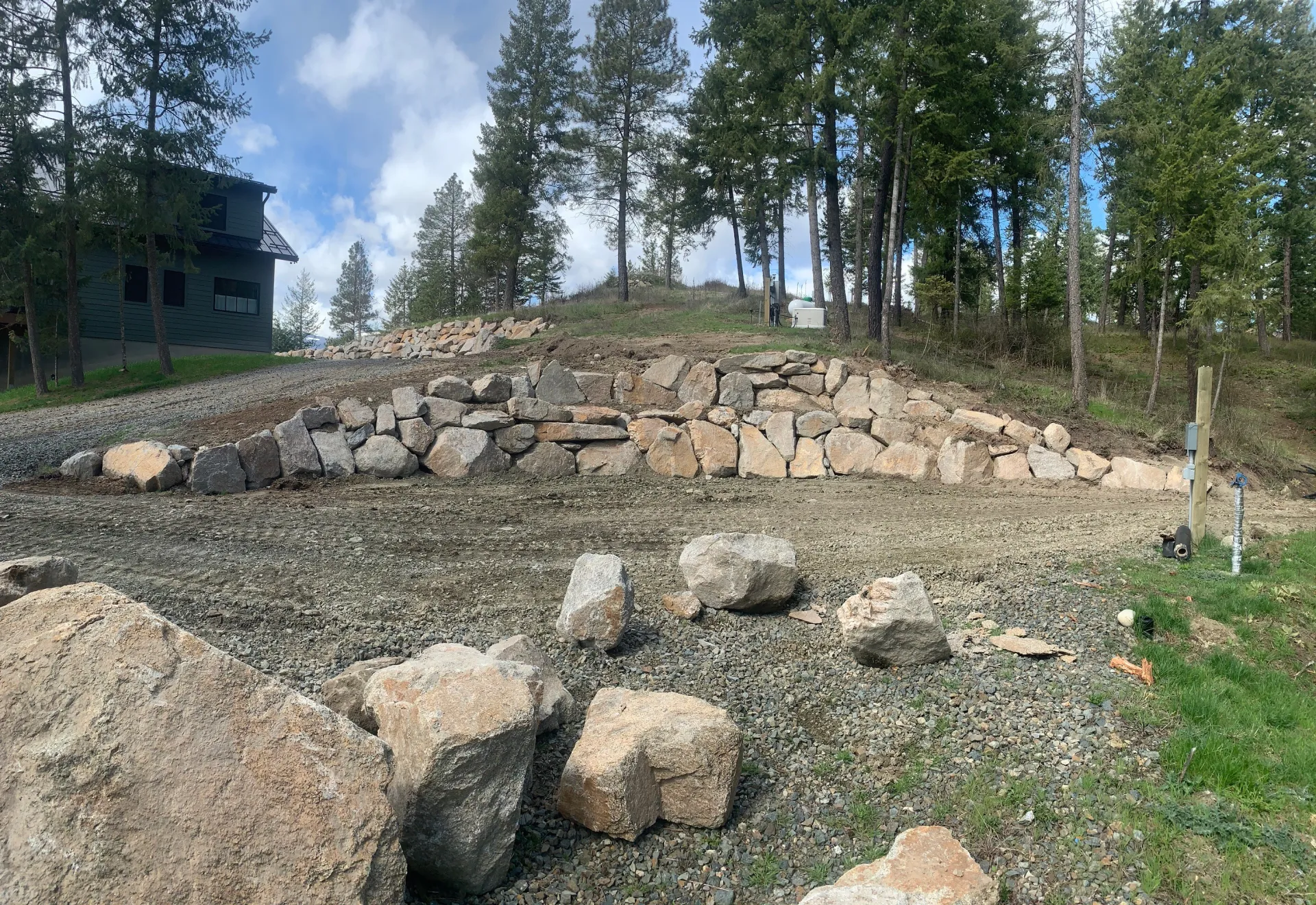 Boulder retaining wall construction on hillside property